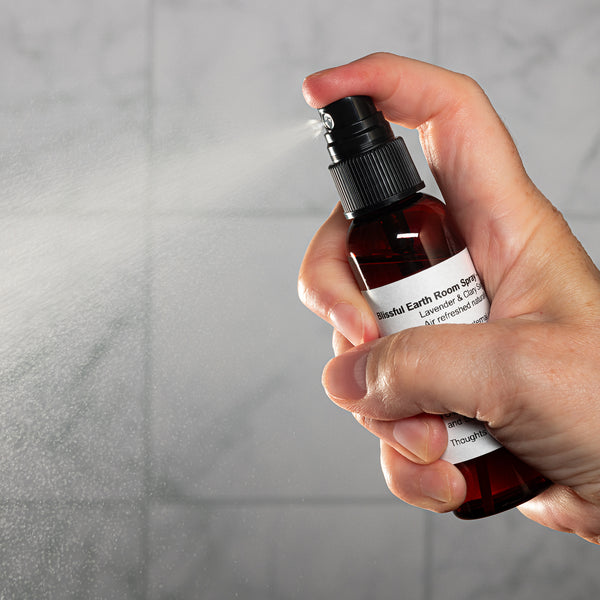 Blissful Earth Room Spray 2oz Lifestyle with Human Hand Spraying Square Microbatch Label
