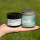 A hand holding two jars of Ora&