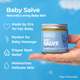 Jar of Baby salve held in a hand with product befits details on a blue background.