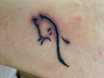Small black tattoo with redness on a person's feet