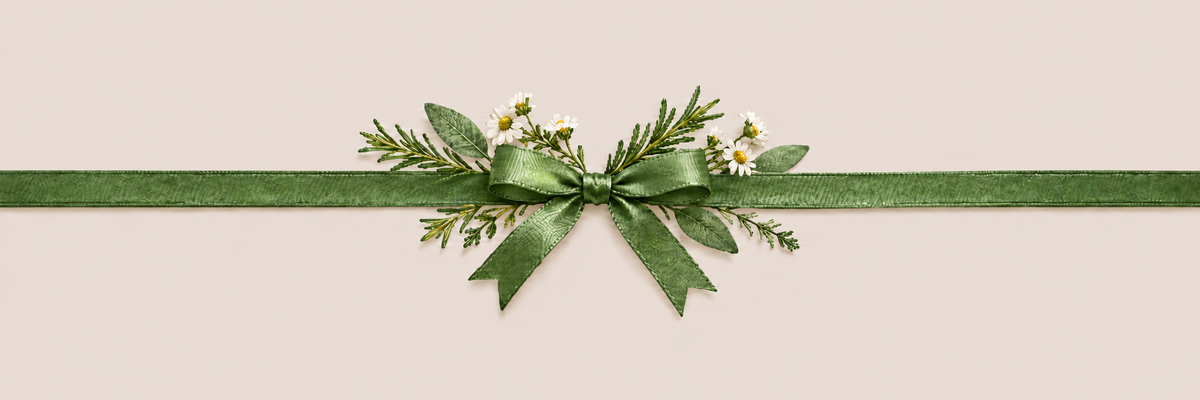 A horizontal dark green ribbon tied into a bow with green pine branches and small white daisy flowers, centered on a light beige background.