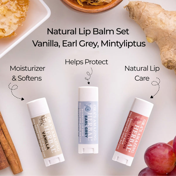 Three lip balm Vanilla, Earl Grey, and Mintyliptus arranged on a light surface with ingredient props including ginger, cinnamon, honey, and grapes. Text reads &