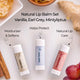 Three lip balm Vanilla, Earl Grey, and Mintyliptus arranged on a light surface with ingredient props including ginger, cinnamon, honey, and grapes. Text reads &