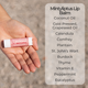 Mintyliptus Lip balm held in a hand with list of ingredients on a blurred background.