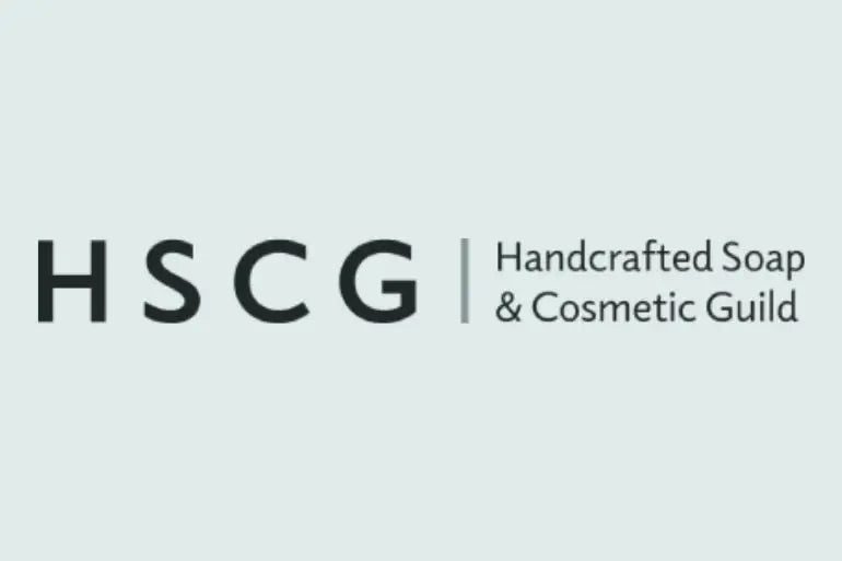 The logo for HSCG (Handcrafted Soap & Cosmetic Guild) in dark gray text on a pale blue-gray background.
