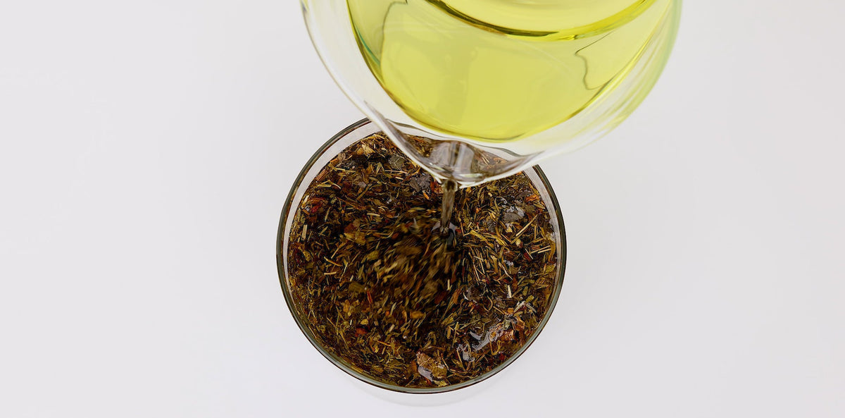 The Amazing Benefits of Pure Grapeseed Oil For the Skin Blog Post Grapeseed Oil Pouring into Herbs
