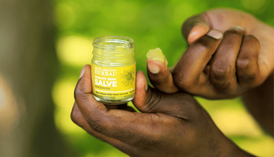 touchy skin salve 1 oz open jar in hand with salve on finger