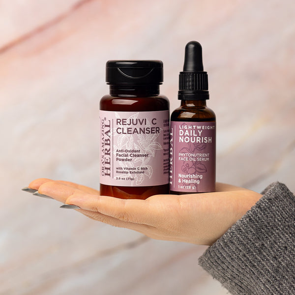 Rejuvi C Cleanser and Lightweight Daily Nourish Held in a Hand Against a Neutral Background